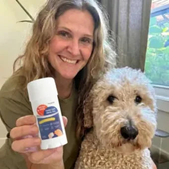 Woman on a couch smiling with her Goldendoodle and a Twist and Lick stick