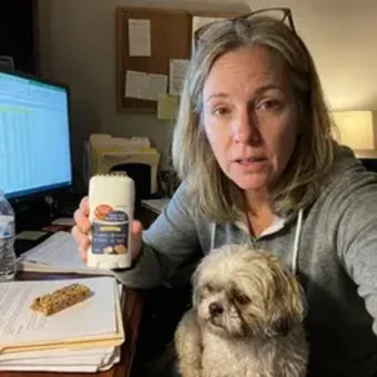 Woman at her desk holding Twist and Lick with her small dog on her lap